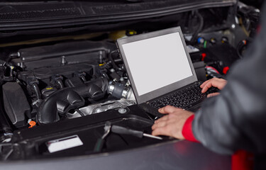 Crop mechanic using laptop while fixing car