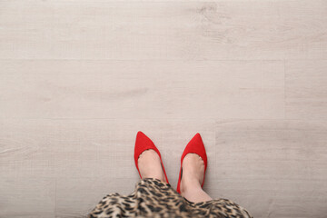 Woman in red shoes standing on wooden floor, top view. Space for text