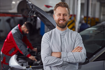 Confident customer near mechanic fixing car