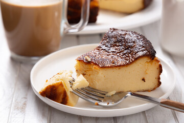 Delicious basque cheesecake portion with a coffee - obrazy, fototapety, plakaty