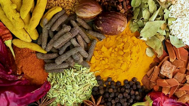 Various spices, peppers and herbs close-up top view in a circular rotation. Eastern spice market.
