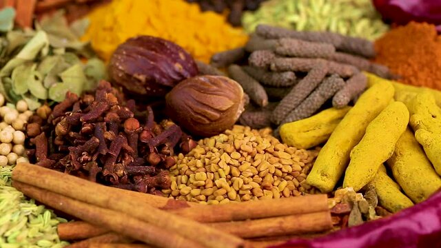 Various spices, peppers and herbs close-up top view in a circular rotation. Eastern spice market.
