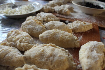 Homemade ugly dumplings lie on a board sprinkled with flour