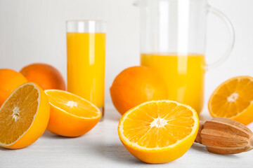 Fresh ripe oranges, juice and reamer on white wooden table