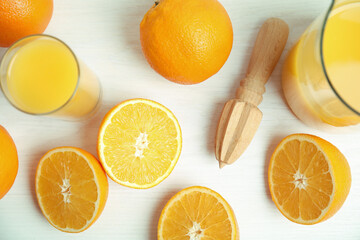 Fresh ripe oranges, juice and reamer on white wooden table, flat lay