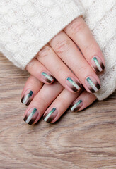 Female hands with black manicure on a wooden background.
