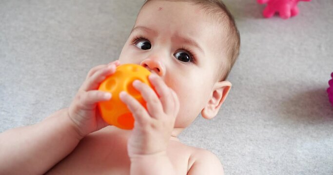 infant, childhood concept - close-up of smiling happy Baby plays with a teether. Teeth cutting. First teeth. Joy toothless 7 months baby bite, gnaws teether toy