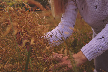 Woman touching flowers in nature.