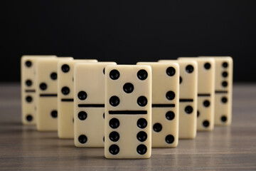 Domino tiles on wooden table against black background, closeup