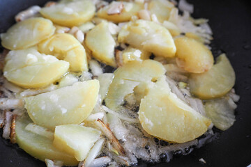 boiled potatoes and onions are fried in rapeseed oil in a pan side view . omelet preparation stage