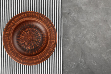 Clay plate and towel on grey table, top view with space for text. Handmade utensil