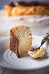 Bitten portion of basque burnt cheesecake on white plate with vintage spoon