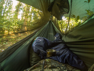 inside view of traveler expedition hammock with sleeping back and metal cup. freedom travel holiday concept
