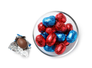Glass bowl with chocolate eggs wrapped in colorful foil on white background, top view
