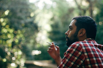 Young man in plaid smoking outside