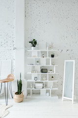 Spacious stylish modern trendy loft apartment in white and light colors. brick wall, wood floor, shelving, pallet bed and teepee-shaped children's house. everything is white with gray tints.
