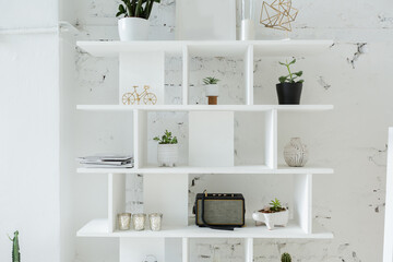 Spacious stylish modern trendy loft apartment in white and light colors. brick wall, wood floor, shelving, pallet bed and teepee-shaped children's house. everything is white with gray tints.