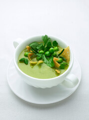 Green pea puree soup on white plate with place for text