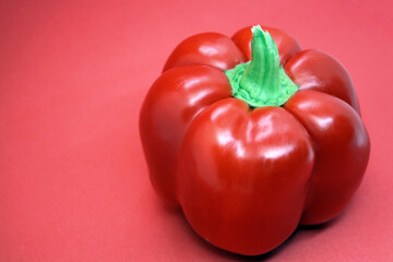 The fruit of a red sweet pepper on a red background.
