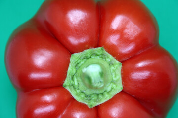 The fruit of a red sweet pepper on a green background.