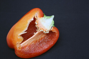 The fruit of a red sweet pepper on a black background.