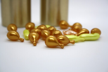 Gold and pink capsules with cosmetic oil for the face.