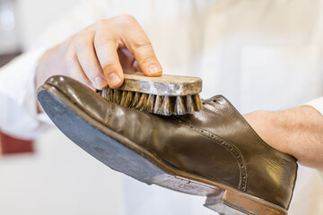 man body and hand restoring parisian brown leather shoes. White shirt with old traditional brush