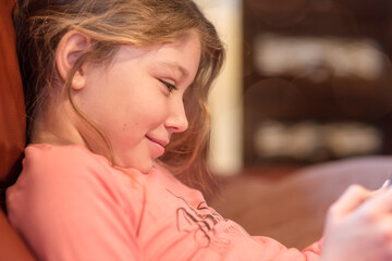 Fototapeta premium Pretty little girl playing or reading on a digital console or tablet