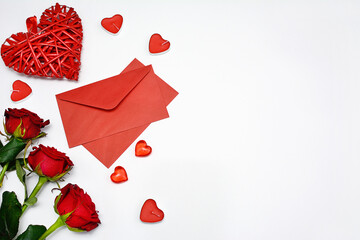 Top view of valentine's day composition on white background. Decorative hearts, red roses, envelopes with side space for design. Women's holidays concept.