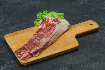 Raw beef bacon over wooden board