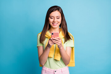 Photo of young beautiful happy positive cheerful smiling girl using smartphone isolated on blue color background