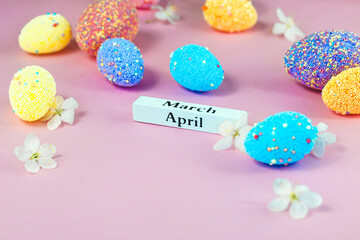 April lettering with Easter eggs and spring flowers on a pink background