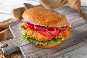 Tasty grilled burger with chicken, turkey, or breaded fish fillets.  Delicious grilled hamburger on a dark background. Free space for text