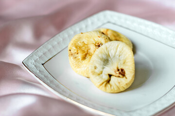 Dried dates on a gold saucer with a gold border on a silk tablecloth.