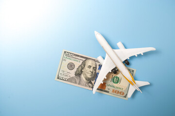 A globe, a toy plane and a 100 dollar bill on blue background. Travel concept