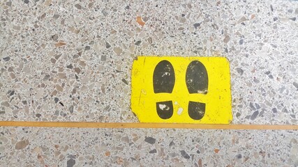 Footprints on a yellow background symbol for Social Distancing. footprint symbol on Marble floor