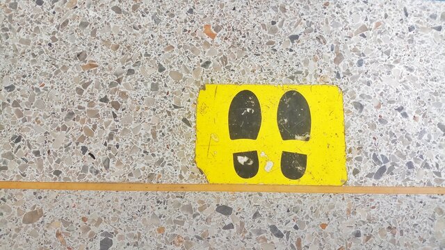 Footprints on a yellow background symbol for Social Distancing. footprint symbol on Marble floor - Powered by Adobe