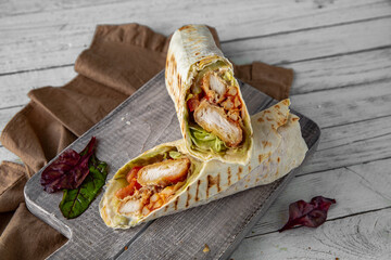 A delicious doner donair kebab wrap with chicken fillet, lettuce, tomato,  onion and sauce.