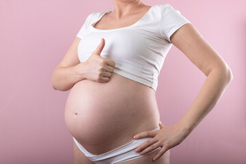 A pregnant woman shows a thumb up. Big pregnant belly.