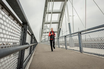 Obraz na płótnie Canvas Active senior woman running through the city during the day.
