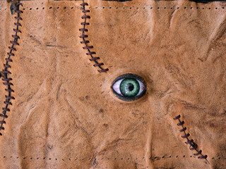 Fresh zombie leather skin with scars stitched with dark brown thread and green bloody eye top view