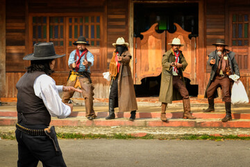 Obraz premium Vintage pictures of a sheriff and a group of cowboy robbers who rob a bank standing face to face. Everyone has a gun in hand, focus on the sheriff.