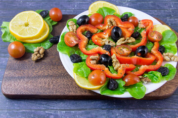 Appetizing vegetable salad with cherry tomatoes, paprika, olives, walnuts, raisins for a healthy diet.