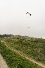 Fototapeta na wymiar Paragliding over the green cliffs on an overcast day