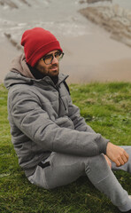 Man on the cloudy shore sitting looking at the sea on the grass