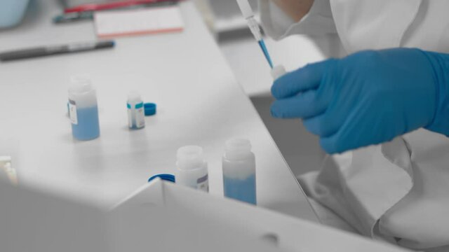 Scientist biologist works with samples of human blood in sterile medical laboratory. Pharmaceutical company conducts research develops and manufactures drugs and vaccine against covid 19