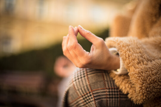 Woman meditating in park. Focus is on hand.