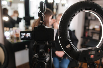 Woman make makeup for attractive blond hair woman in studio. Selective focus of digital camera with makeup artist applying cosmetics for beautiful model