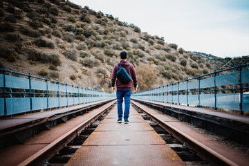 Young man on train track bridge