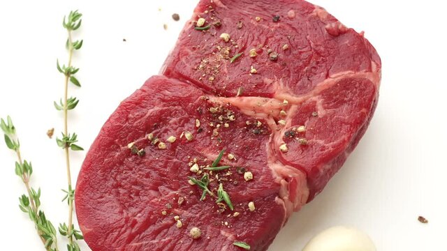close up of rotating spicy raw beef steak meat on white background, top view